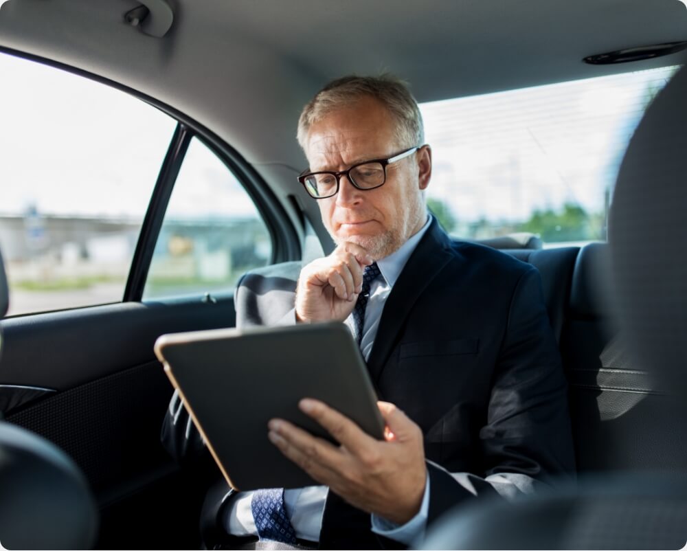 A man deep in thought inside a car, sitting with his work tablet A man deep in thought inside a car, sitting with his work tablet