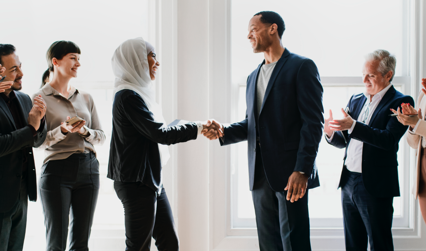 A male and female employees shaking hands as to agree on a decision
